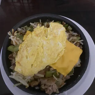Skillet with scrambled eggs, onions, peppers, and American Cheese.