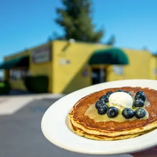 a person holding a plate of pancakes