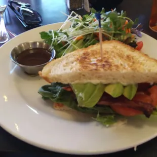 Bacon, lettuce, tomato and avocado sandwich with fresh greens on the side
