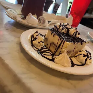 a slice of cheesecake with chocolate sauce and whipped cream