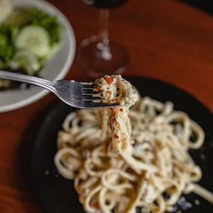 a fork lifting a piece of pasta from a plate