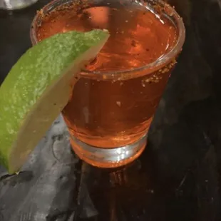 a shot of a drink with a lime wedge