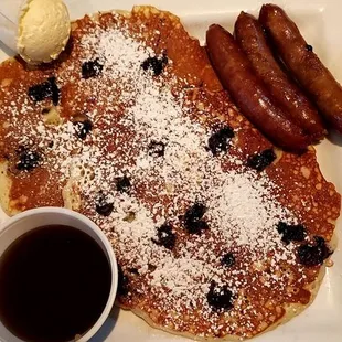 Two blueberry hot cakes with sausage, syrup, and butter