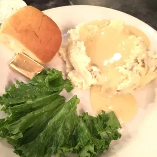 Mashed potatoes and gravy, dinner roll.