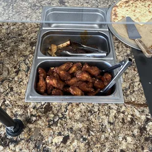a tray of chicken wings and a pizza
