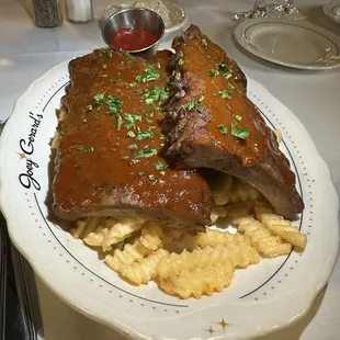 BEVERLY MAE&apos;S RIBS Full baby back rack ribs, slow-cooked and charred, served with house-made BBQ sauce, crinkle-cut fries, coleslaw