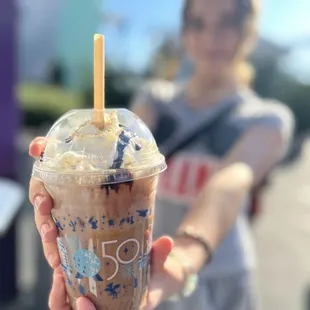 a woman holding a cup of iced coffee