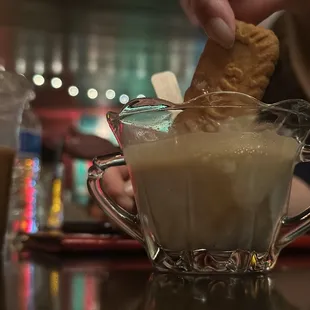 a person dipping a cookie into a cup of coffee