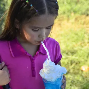 a young girl holding a drink and a baseball bat