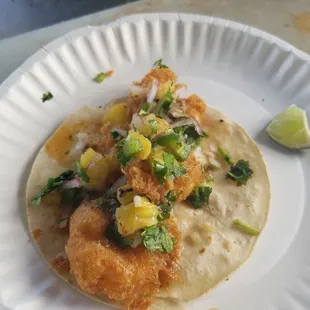 a fish taco on a paper plate