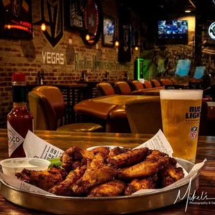 a plate of chicken wings and a pint of beer