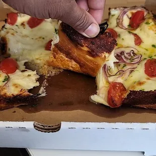 a hand grabbing a slice of pizza