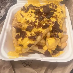 a tray of fries with cheese and bacon