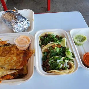 Our order today. Quesadilla left front, cali burrito  back left, right, 3 types of tacos with hot and mild sauces on the side