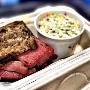 a sandwich and coleslaw in a styrofoam container
