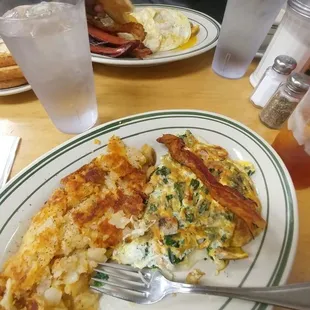 Spinach, sausage, mozzarella omelette. Home fries. Over there: over easy eggs with beef sausage and bacon.