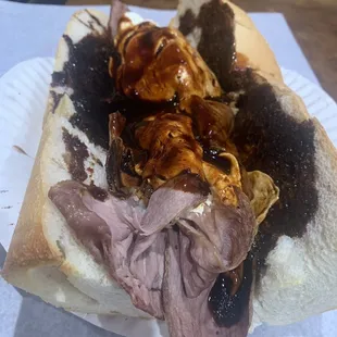 a roast beef sandwich on a paper plate