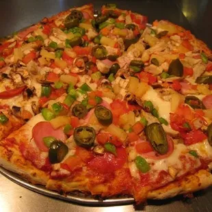 This pizza has pepperoni, ham, pineapple, green onion, tomato, garlic chicken chunks, jalapenos, and mushrooms.