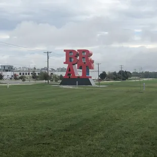 a large red sculpture in the middle of a grassy field