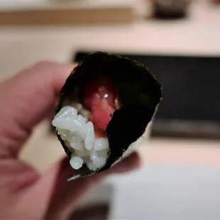 a hand holding a piece of sushi
