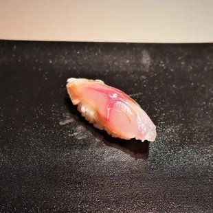 a piece of sushi on a black plate