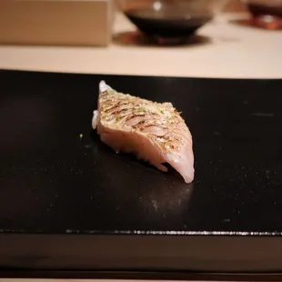 a piece of sushi on a black plate