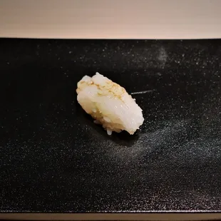 a piece of sushi on a black plate