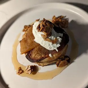 a plate of french toast topped with whipped cream and walnuts