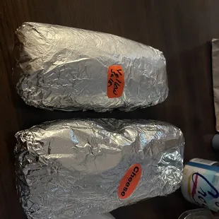 two burritos wrapped in tin foil