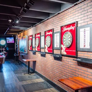 a brick wall with a row of tables and a row of darts