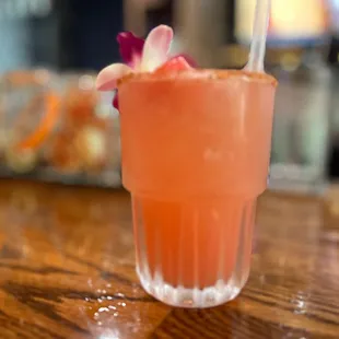 a pink drink with a flower garnish