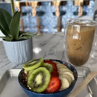 a bowl of fruit and a glass of iced coffee