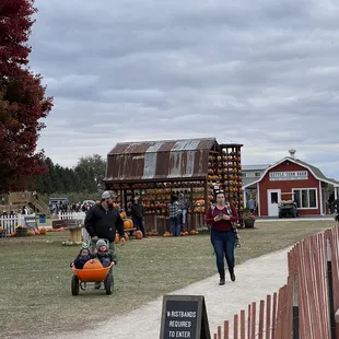 a woman pushing a stroller in front of a barn