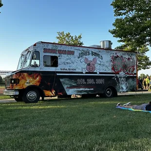 a woman sitting on the grass in front of a food truck