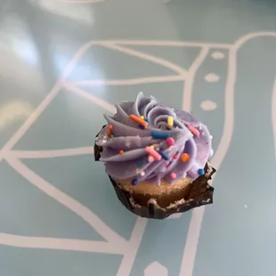 a cupcake with purple frosting and sprinkles