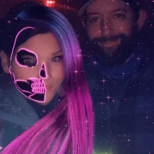 a man and a woman with pink hair and a neon skull mask