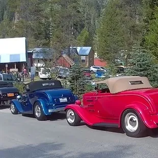 a line of antique cars parked along the side of the road