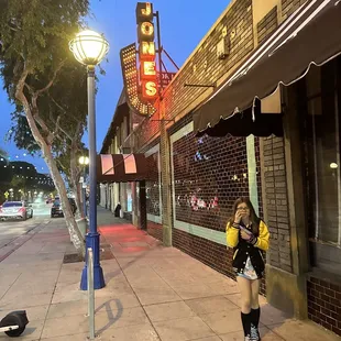 a woman walking down the sidewalk in front of a motel
