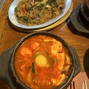 Japchae and soft tofu mushroom soup with egg to be stirred into the piping hot broth.