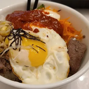 a bowl of food with a fried egg on top