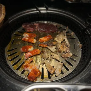 Spicy pork belly and normal pork belly with some steak cooking in the back