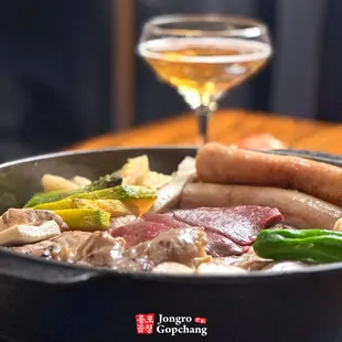 a bowl of food with a glass of wine in the background
