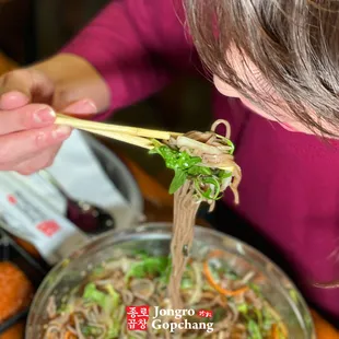 a woman eating noodles with chopsticks