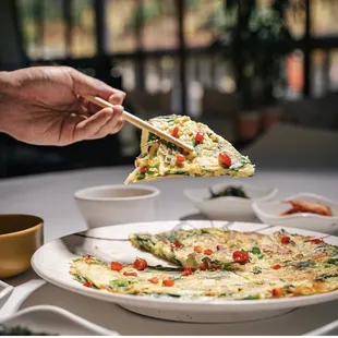 a person holding chopsticks over a plate of food