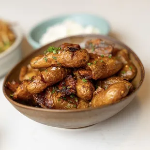 a bowl of cooked potatoes and a bowl of dips