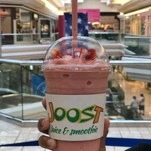 a hand holding a smoothie in a mall