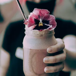 a person holding a jar with a flower in it