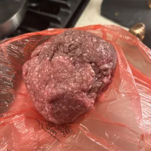 a ground beef burger wrapped in plastic