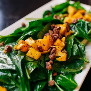 a plate of spinach and squash salad