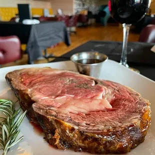 a piece of meat on a plate with a sprig of rosemary